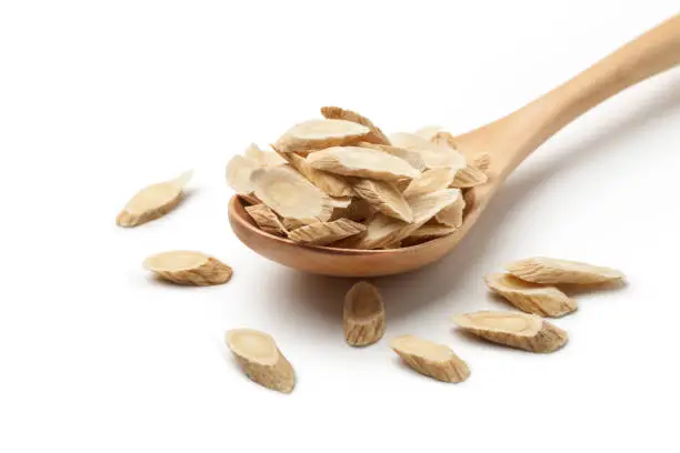 Sliced ​​of Astragalus (Huang Qi) in a wooden spoon, Isolated on white background. Chinese herbal medicine.