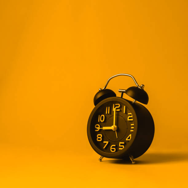 istock Black alarm clock on yellow background. 1152540213