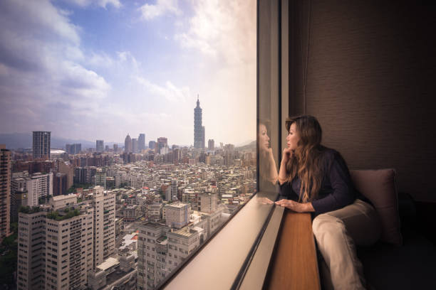 mulher asiática que olha fora do indicador, apreciando a vista de taipei, formosa - window office building taipei built structure - fotografias e filmes do acervo