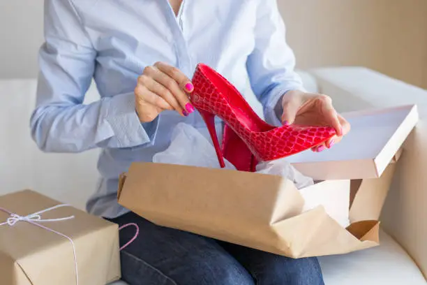 Photo of Woman unpacking new shoes delivered by post