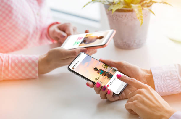 Two women using their mobile phones together Two unrecognisable Caucasian ethnicity females using their mobile phones together people sharing photos stock pictures, royalty-free photos & images