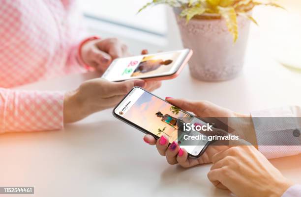 Two Women Using Their Mobile Phones Together Stock Photo - Download Image Now - Auto Post Production Filter, Social Media, Influencer
