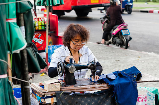 A woman working at the sewing machine in the street. December 2011