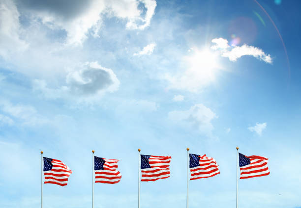 Conceptual image of waving American flags hanged at tall pole in a row over clear blue sky