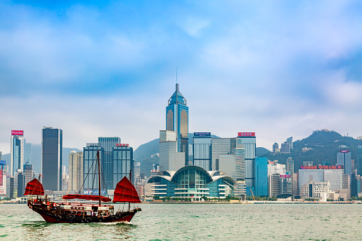 Old Wooden Tourist Junk Ferry Boat In Victoria Harbor Against Famous