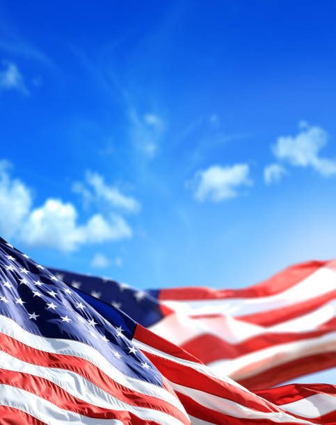 close up waving American flags over sunny cloudy blue sky
