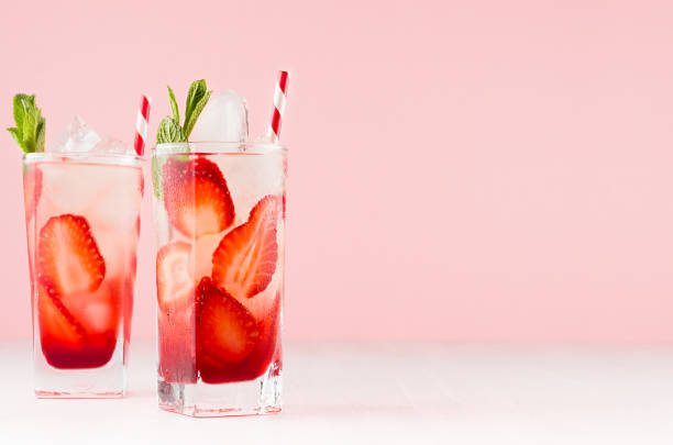 istock Tropical refreshing fruit drink with slices strawberry, green mint, ice, straw on soft light white wood board, pastel pink interior. 1152567680