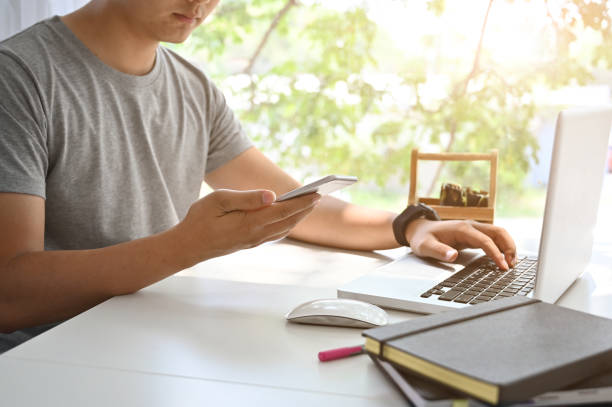 istock Closeup asian man using laptop and mobile phone on table. 1152568593