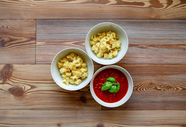 Topview of Ravioli and Tomato sauce served on a wooden table.