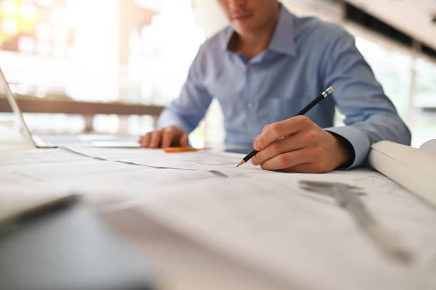 istock Architect man working on blueprint with engineer planing on office desk. 1152568776