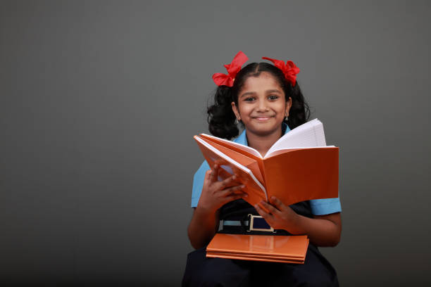 istock Little girl wearing school uniform holds a book 1152571613