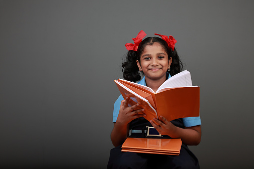 Little girl wearing school uniform holds a book