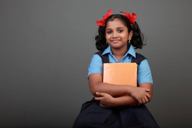 Little girl wearing school uniform holds a book