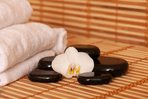 istock Black massage rocks decorated with flower in a dark and light bamboo background 1152571789