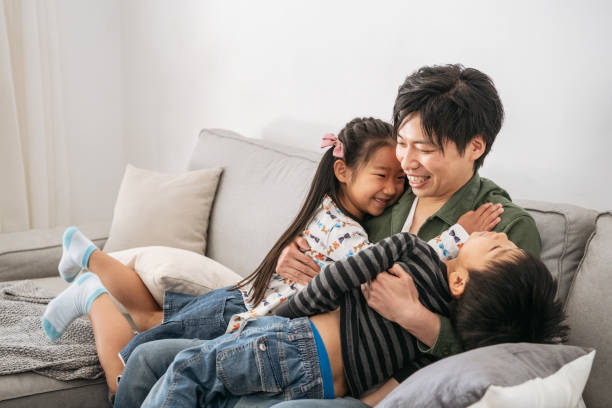 istock Affectionate father cuddling young son and daughter on sofa 1152571856