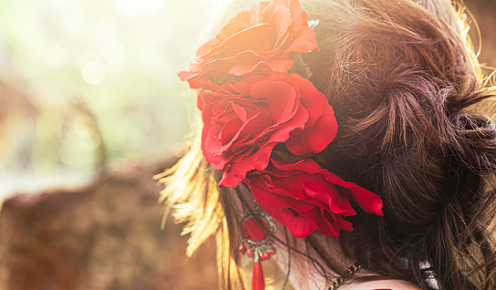 Cropped close-up photo of hair with red flowers in her hair. Copy space