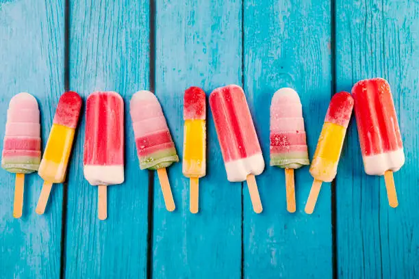 Colorful fruit ice cream stick look fresh to eat placed on a blue vintage wooden floor