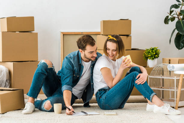 istock smiling couple with notebook sitting on carpet near cardboard boxes and drinking coffee 1152582484