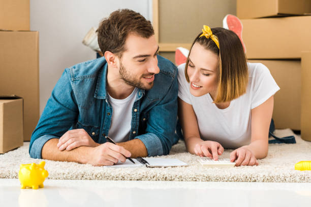 istock smiling couple lying on carpet with notebook, pen and calculator 1152582503