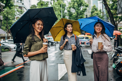 Three women, three young ladies standing on the street on Taipei on a rainy day.