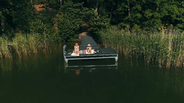 istock Friends relaxing on a lake pier. Summer activities 1152586335