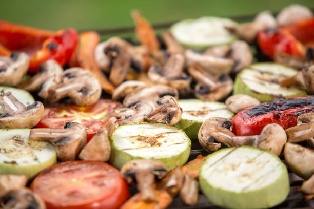 Healthy food preparing outdoors on summer or spring picnic. Grilled vegetables on grill on coals. Barbecue picnic on a meadow