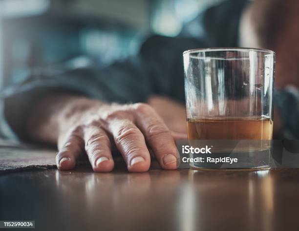 Hand By Glass Of Liquor Mans Head On Table Stock Photo - Download Image Now - Alcohol Abuse, Drunk, Men