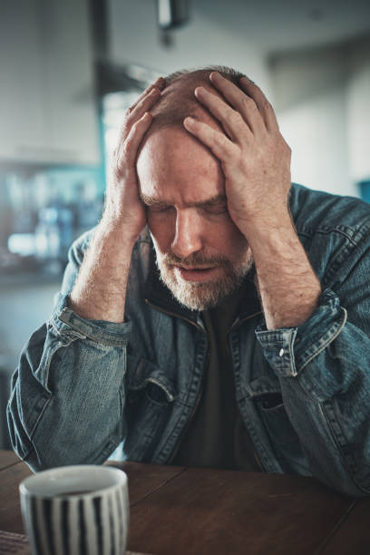 Desperate and depressed mature man, head in hands A desperate and depressed mature man sits at a table, his head in his hands, looking devastated. divorcee stock pictures, royalty-free photos & images