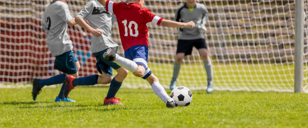 мальчики играют в футбол. мальчики пинают футбол на спортивной площадке - playing field kids soccer goalie soccer player стоковые фото и изображения
