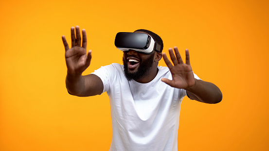 Happy African-American man using VR headset exploring future technologies