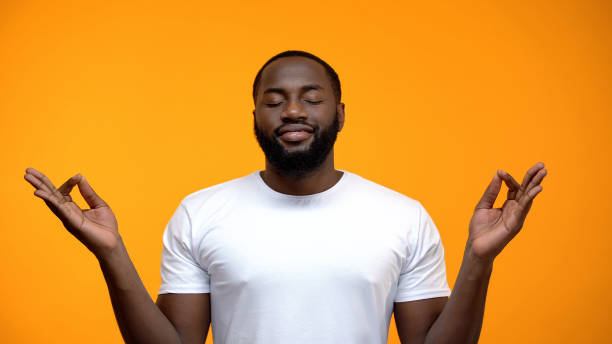istock Pacified black man meditating against yellow background, breathing exercises 1152598862