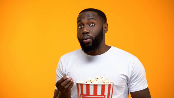 istock Excited African-American male with popcorn watching interesting TV program 1152598948