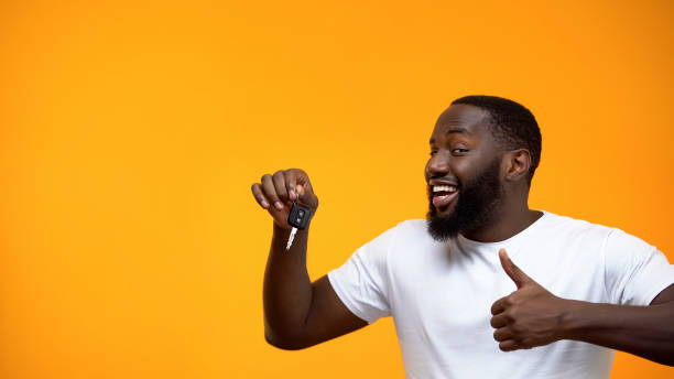 Excited Afro-American man holding car key and showing thumbs up, purchase Excited Afro-American man holding car key and showing thumbs up, purchase car key photos stock pictures, royalty-free photos & images