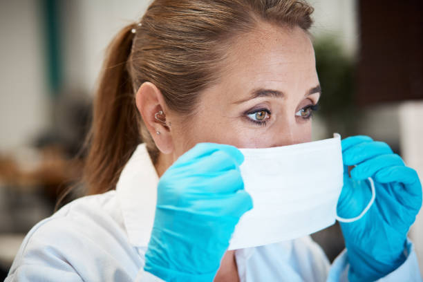 female scientist or health professional putting on mask - csi imagens e fotografias de stock