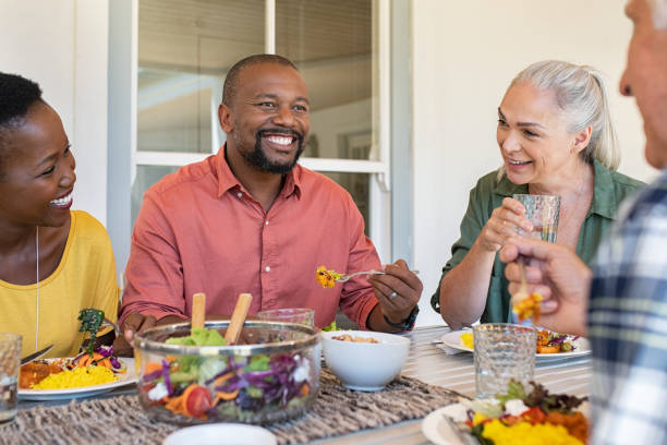 wieloetnicznej dojrzałych mężczyzn i kobiet jedzących lunch - dining senior adult friendship mature adult zdjęcia i obrazy z banku zdjęć