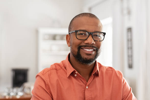 African mature man with spectacles Smiling mature man wearing spectacles looking at camera. Portrait of black confident man at home. Successful entrepreneur feeling satisfied. mid adult stock pictures, royalty-free photos & images