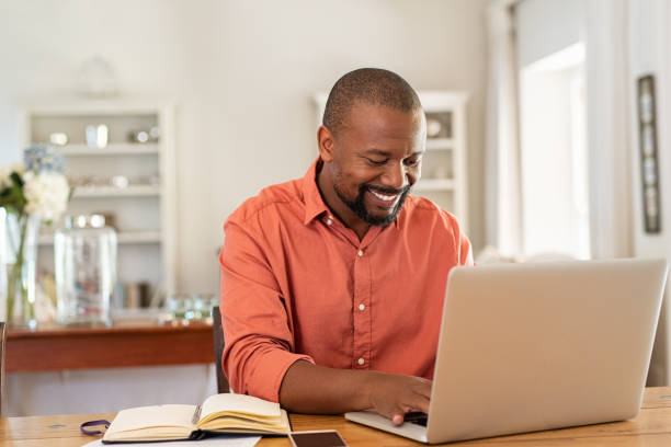 szczęśliwy dojrzały czarny człowiek za pomocą laptopa - telecommuting technology equipment one person zdjęcia i obrazy z banku zdjęć