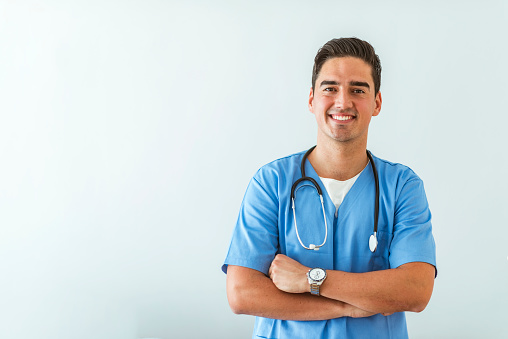 Portrait of a smiling doctor. Doctor with stethoscope standing, crossed arms, isolated on bright background. Portrait of a friendly doctor smiling at the camera.