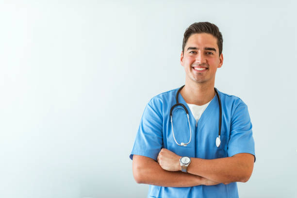 Young doctor Portrait of a smiling doctor. Doctor with stethoscope standing, crossed arms, isolated on bright background. Portrait of a friendly doctor smiling at the camera. medical supplies photos stock pictures, royalty-free photos & images
