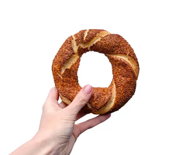 Photo of Traditional Turkish bagel simit in female hand isolated on white background