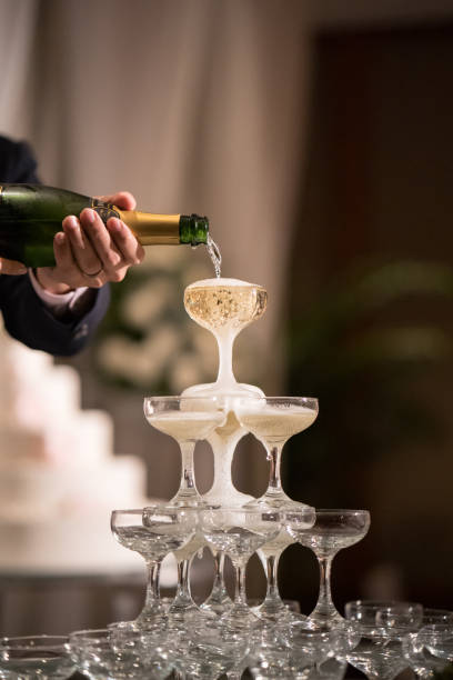 Pouring Champaign into glasses tower in wedding reception Pouring Champaign into glasses tower in wedding reception tower stock pictures, royalty-free photos & images