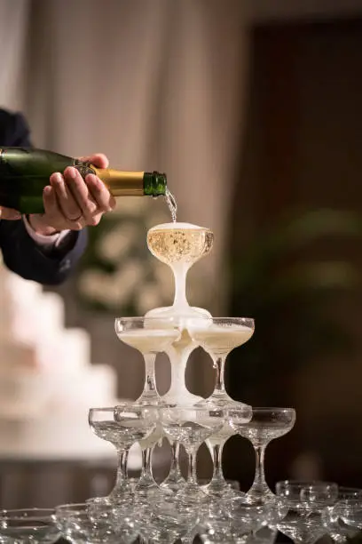Pouring Champaign into glasses tower in wedding reception