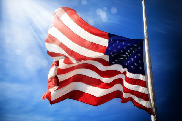 istock waving American flag at flagpole over sunny blue sky 1152617141