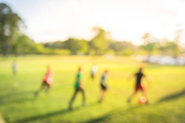 sfondo sfocato ragazzi latinoamericani che giocano a calcio al parco durante il tramonto - football player group of people running american football foto e immagini stock