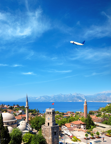 imagen del paisaje urbano del distrito histórico de Antalya y el avión volador sobre el mar Mediterráneo y las altas montañas photo