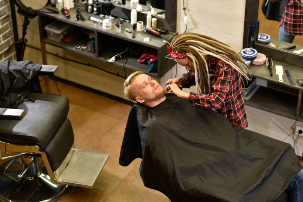 istock a barber with dreadlocks cuts a beard to a brutal man in the salon 1152624957