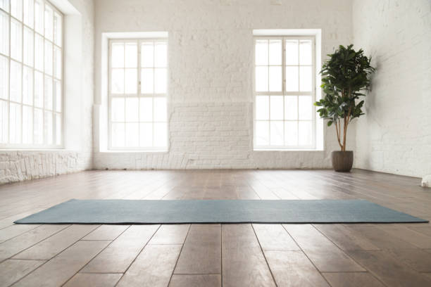 alfombra de yoga desenrollada en suelo de madera en estudio de yoga - pilates health club gym exercising fotografías e imágenes de stock