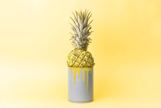 istock Creative idea: pineapple in a can with yellow paint on a uniform yellow background. 1152630484