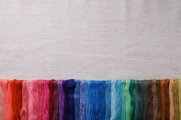 Colorful yarns for embroidering. Multicolored thread lined in a row on a canvas background. Top view of a mockup