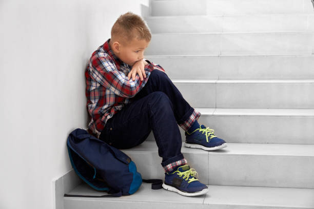 istock Little school boy sitting alone on stairs on school. 1152637228